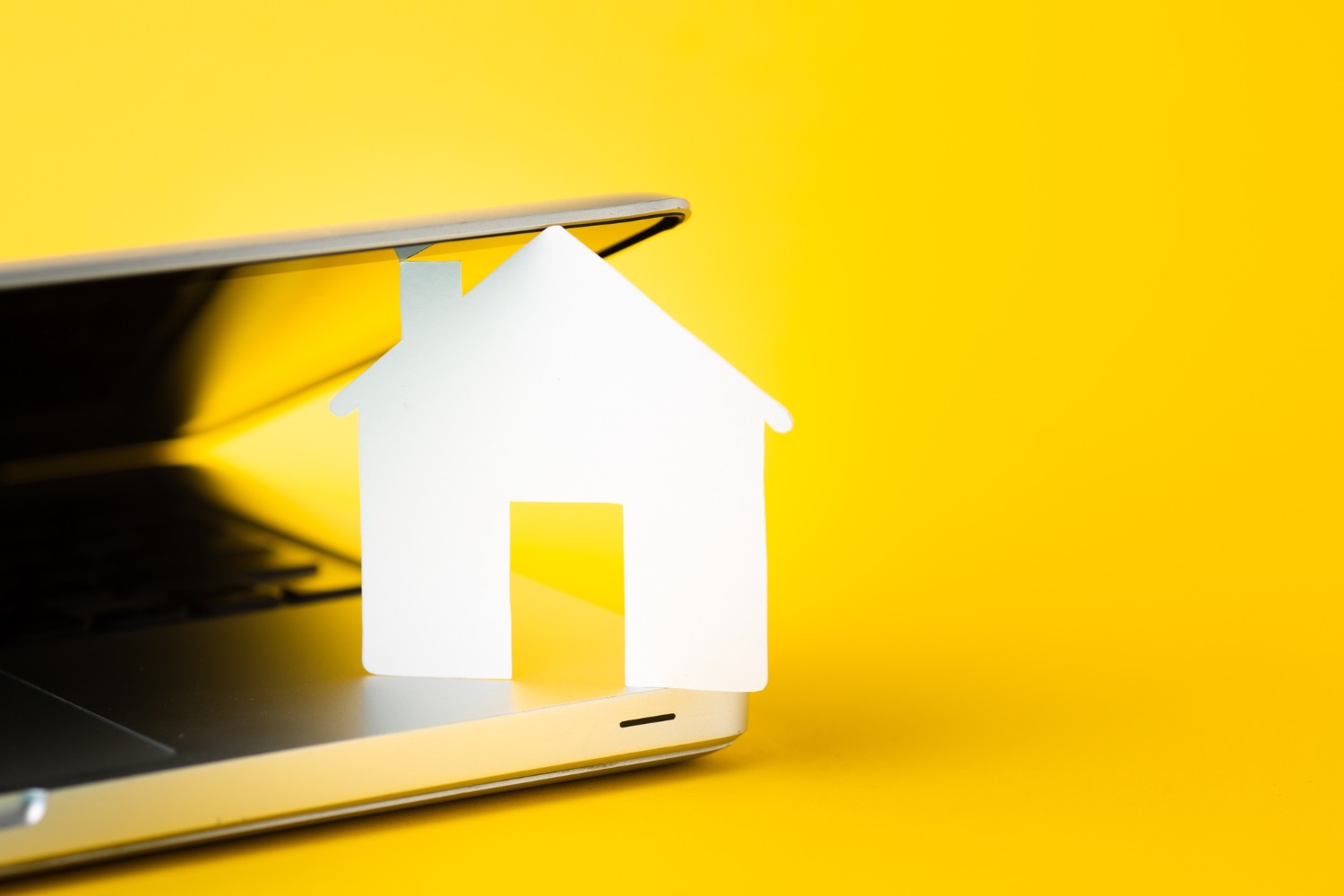 A paper house resting on a laptop